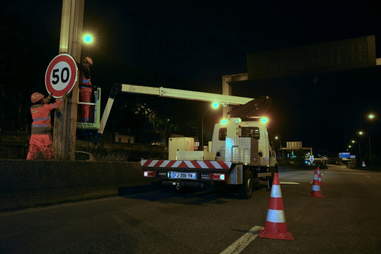 Un ouvrier installe un panneau de limitation à 50 km/h sur le périphérique au niveau de la porte d'Ivry, à Paris, le 30 septembre 2024