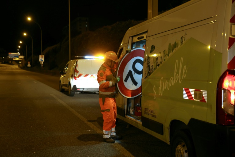 Un ouvrier range un panneau de limitation à 70 km/h, sur le périphérique au niveau de la porte d'Ivry, le 30 septembre 2024 à Paris