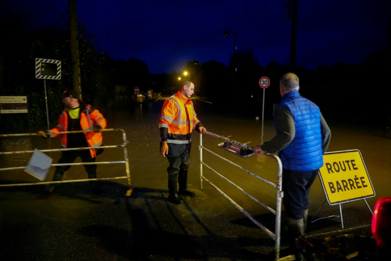 Des ouvriers placent une barrière dans une rue inondée à Pommeuse, dans le département de Seine-et-Marne, à l'est de Paris, le 10 octobre 2024