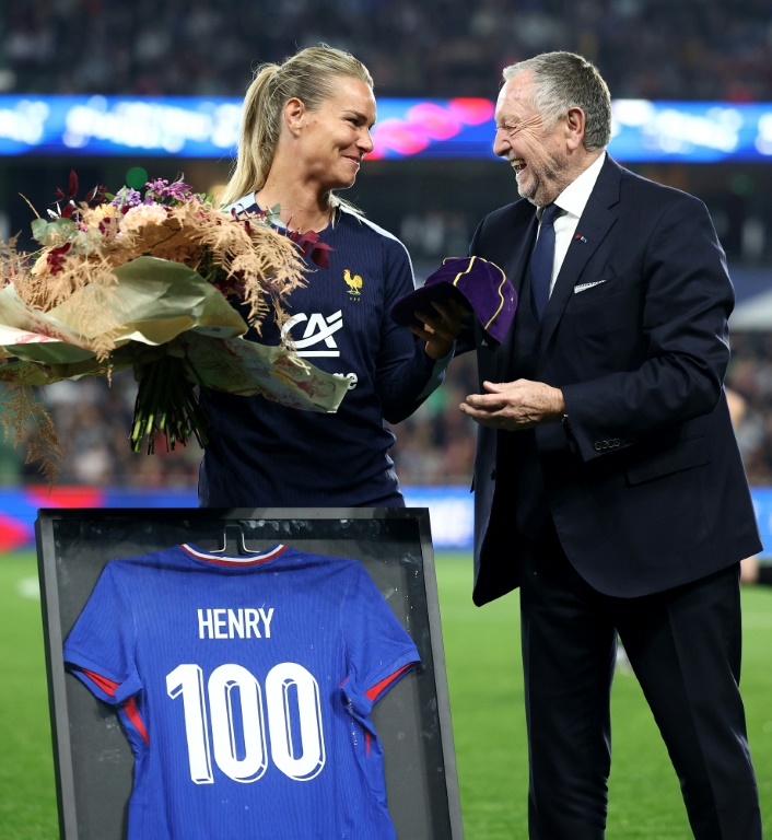 La milieu de terrain Amandine Henry (G) reçoit un bouquet, un maillot et une casquette commémoratifs marquant ses 100 sélections en équipe nationale, de l'ancien président du club de football de l'Olympique Lyonnais Jean-Michel Aulas (D) avant le match de qualification pour l'UEFA Euro 2025 entre la France et la République d'Irlande à Metz, le 5 avril 2024