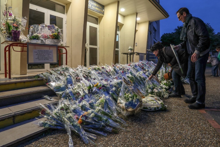 Des habitants rendent hommage à Dominique Bernard, professeur de français, devant le lycée Gambetta, le 13 octobre 2023 à Arras