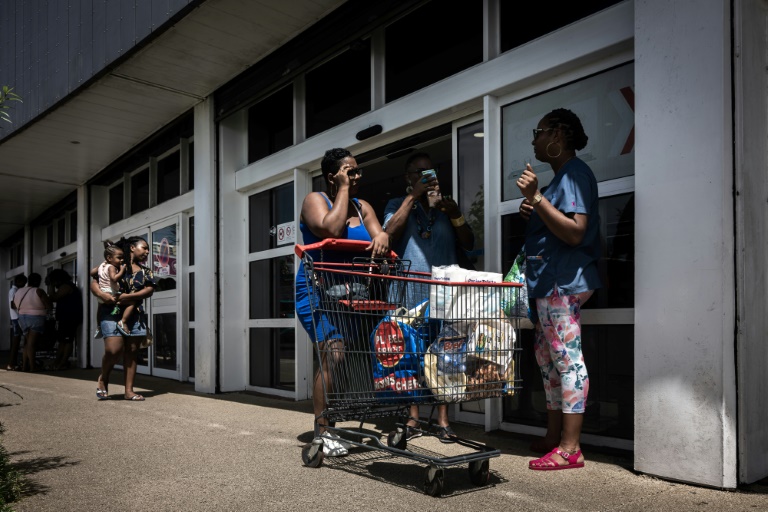 Des habitantes discutent après avoir fait leurs courses dans un supermarché de Fort-de-France, en Martinique, le 14 octobre 2024, dans un contexte d'émeutes liées à la vie chère