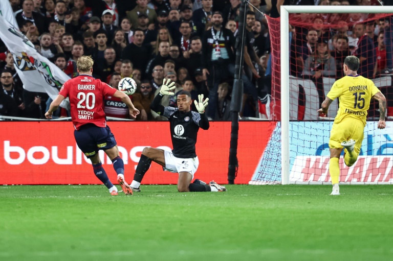 Le défenseur de Lille, Mitchel Bakker (L), marque le second but de la rencontre devant le gardien de Toulouse, Guillaume Restes (C), et offre la victoire à son équipe lors du match de L1 entre le Lille LOSC et le Toulouse FC à Villeneuve-d'Ascq, le 5 octobre 2024