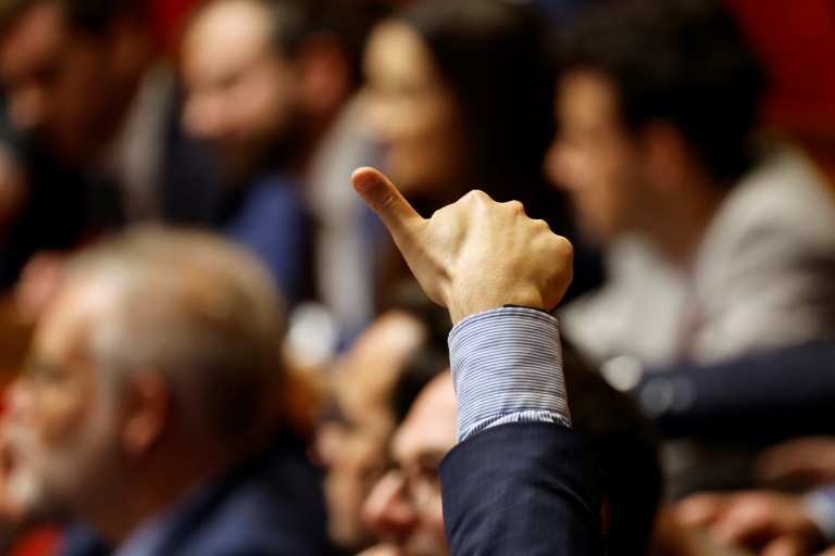 Un député français lève le pouce indiquant le vote de son groupe pour un vote public lors d'une session de débat sur le projet de budget 2025, à Paris, le 22 octobre 2024