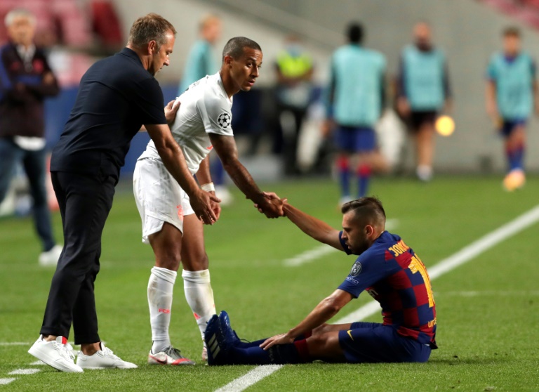 Hansi Flick, alors entraîneur du Bayern Munich, et Thiago Alcantara aident le Catalan Jordi Alba à se relever lors de la victoire du club allemand face au FC Barcelone en quart de finale de la Ligue des champions le 14 août 2020 au stade de la Luz à Lisbonne