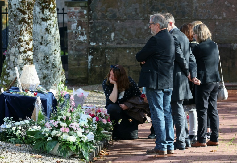 Des proches rassemblés devant des gerbes de fleurs à l'entrée de l'église Saint-Arnoud, lors des funérailles de Lina, le 25 octobre 2024 au village de Plaine, dans le Bas-Rhin