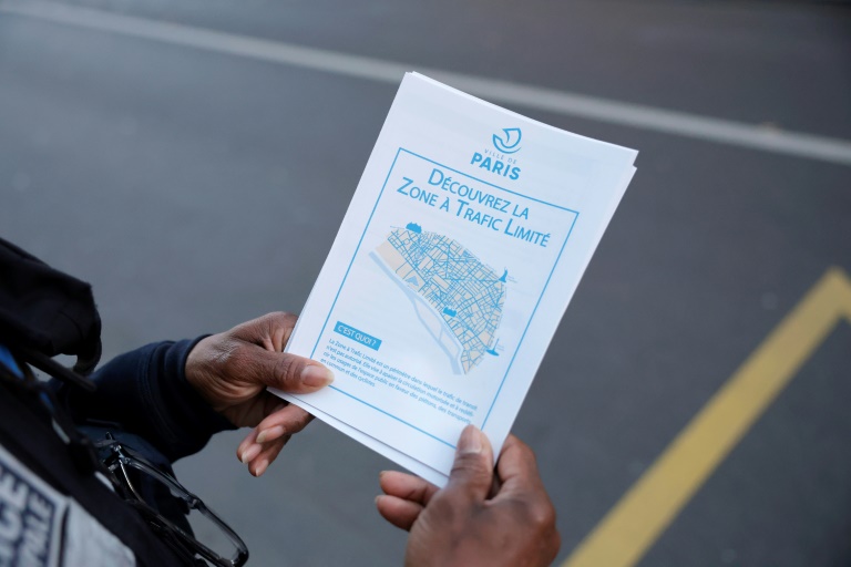 Un policier distribue un dépliant sur la ZTL lors du lancement officiel de la zone à circulation limitée (ZTL) interdisant aux véhicules de la traverser, le 4 novembre 2024 à Paris