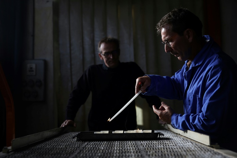 Laurent Lacoste (g) et Thierry Samar (d) contrôlent la qualité des bougies votives destinées à la cathédrale Notre-Dame de Paris, à la Ciergerie de Lourdes, le 7 novembre 2024 dans les Hautes-Pyrénées