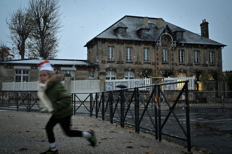 Un enfant passe devant une école sous la neige, à Luc-sur-Mer, dans le nord-ouest de la France, le 21 novembre 2024