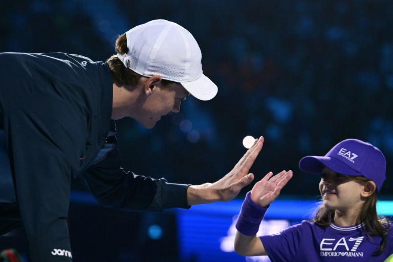 L'Italien Jannik Sinner salue l'enfant qui l'a accompagné lors de son entrée sur le court avant son match contre l'Américain taylor Fritz le 12 novembre 2024 à Turin