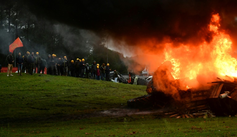 Des agriculteurs se tiennent à côté d'un feu lors d'une manifestation organisée par la Coordination Rurale pour bloquer l'entrée de la centrale d'achat des supermarchés Leclerc à Mont de Marsan, le 20 novembre 2024