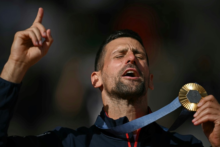 Le Serbe Novak Djokovic avec sa médaille d'or sur le podium des JO-2024 le 4 août 2024 à Roland-Garros