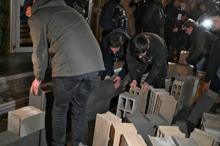 Des agriculteurs érige un mur en parpaings devant l'entrée de l'Inrae, le 28 novembre 2024 à Paris