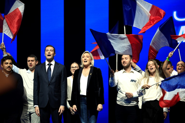 Le président du Rassemblement national Jordan Bardella (3e à gauche) et la présidente du groupe RN à l'Assemblée nationale Marine Le Pen (5e à gauche) chantent lors d'un meeting, le 6 octobre 2024 à Nice (Alpes-Maritimes)