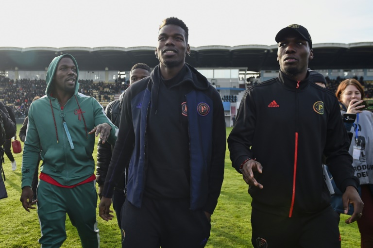 Le footballeur français Paul Pogba (c) et son frère Mathias Pogba (g) marchent sur le terrain avant un match de football entre All Star France et la Guinée au stade de la Vallée du Cher à Tours, le 29 décembre 2019