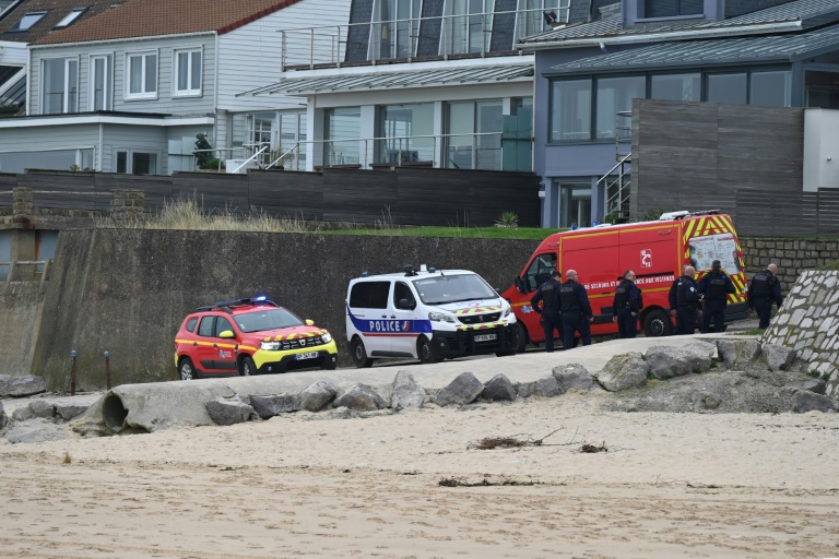 Des policiers transportent un corps découvert sur la plage de Sangatte, près de Calais, d'où de nombreux migrants tentent la  traversée de la Manche, le 2 novembre 2024 dans le Pas-de-Calais