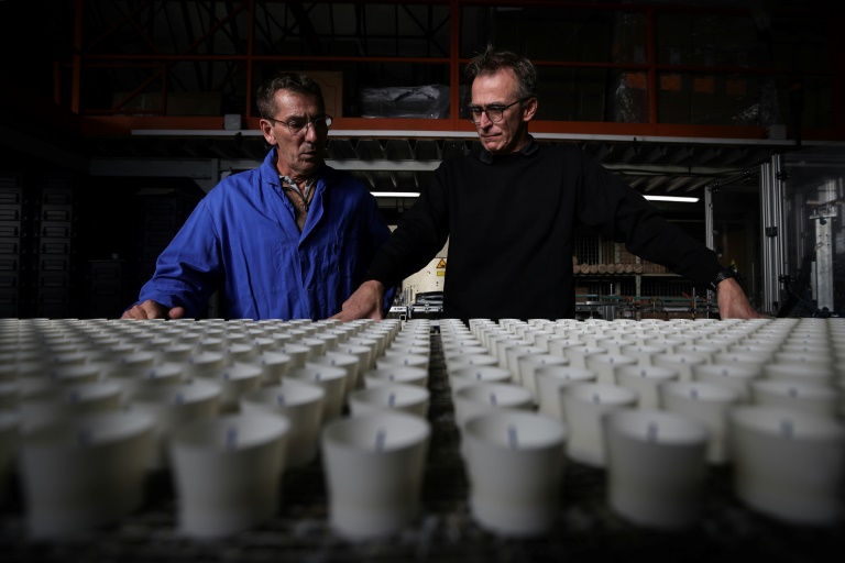 Laurent Lacoste (d), directeur de production, et Thierry Samar (g), directeur technique, devant une ligne de production de bougies votives à la Ciergerie de Lourdes, le 7 novembre 2024 dans les Hautes-Pyrénées