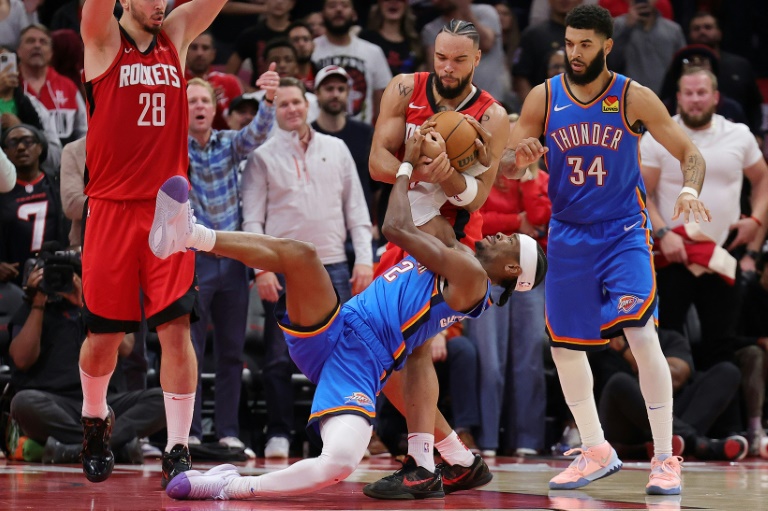 Dillon Brooks (C), des Rockets, et Shai Gilgeous-Alexander (#2), du Thunder d'OKC, à la lutte pour le ballon lors d'un match de saison régulière de NBA, le 1er décembre 2024 à Houston