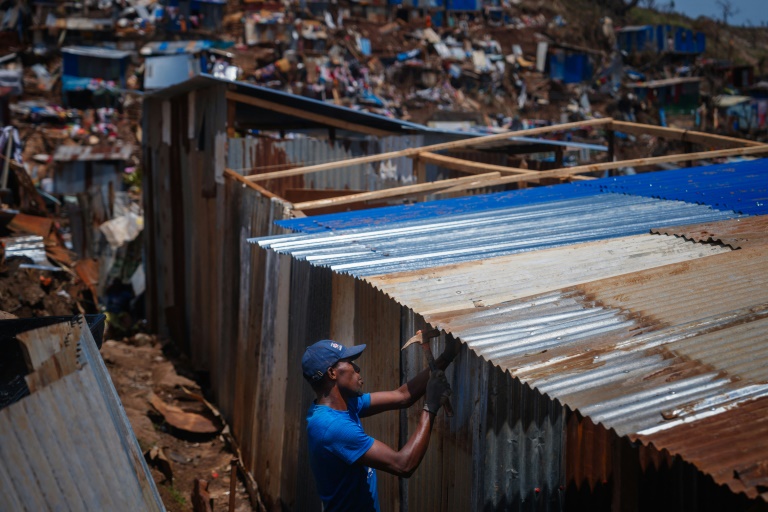 Un habitant du bidonville de Kawéni fixe des tôles pour réparer sa maison endommagée par le passage du cyclone Chido, le 20 décembre 2024 à Mamoudzou