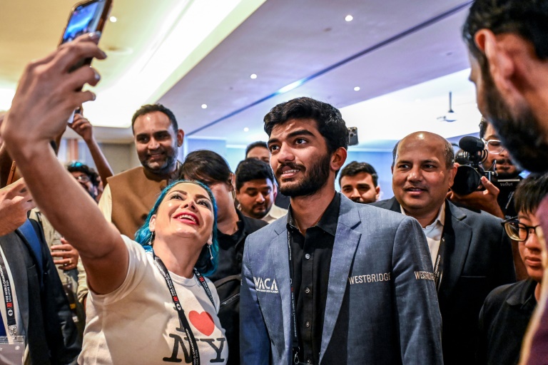 Un fan prend un selfie avec le grand maître indien Gukesh Dommaraju (c.) après sa victoire contre le grand maître chinois Ding Liren dans la 14e partie du Championnat du monde d'échecs, à Singapour, le 12 décembre 2024