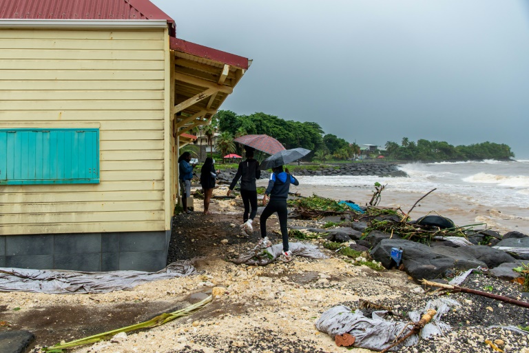 Des promeneurs passent sur la grêve encombrée de débris après le passage de la tempête Fiona à Capesterre-Belle-Eau, en Guadeloupe, le 17 septembre 2022