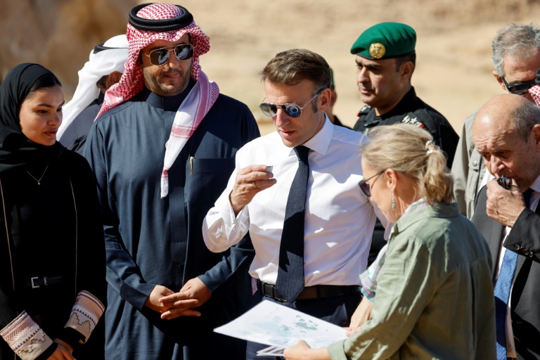 Le président français Emmanuel Macron (c) boit du thé pendant la visite de la cité nabatéenne d'Hégra, près de l'oasis d'Al-Ula, le 3 décembre 2024 en Arabie saoudite