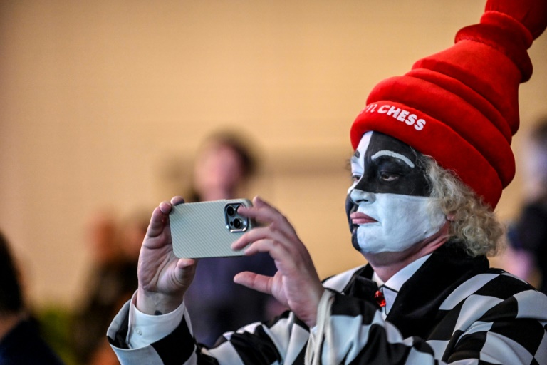 Un fan déguisé en échiquier prend une photo alors que le grand maître d'échecs chinois Ding Liren et le grand maître indien Gukesh Dommaraju s'affrontent dans la 14e partie du championnat du monde d'échecs, à Singapour, le 12 décembre 2024