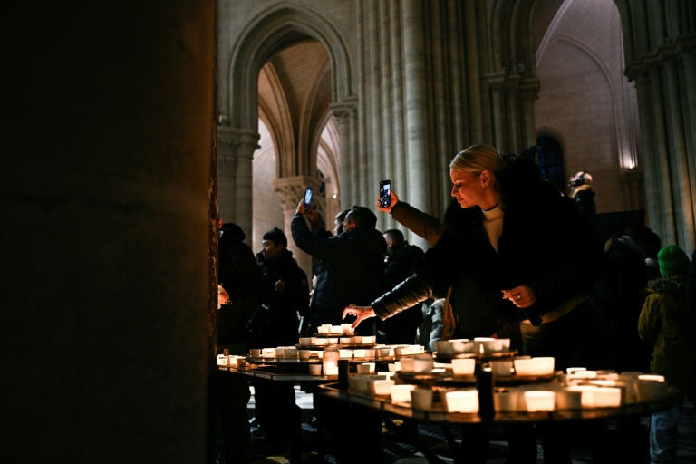 Des personnes allument des bougies lors d'une messe de Noël célébrée à la cathédrale Notre-Dame de Paris, le 24 Decembre 2024