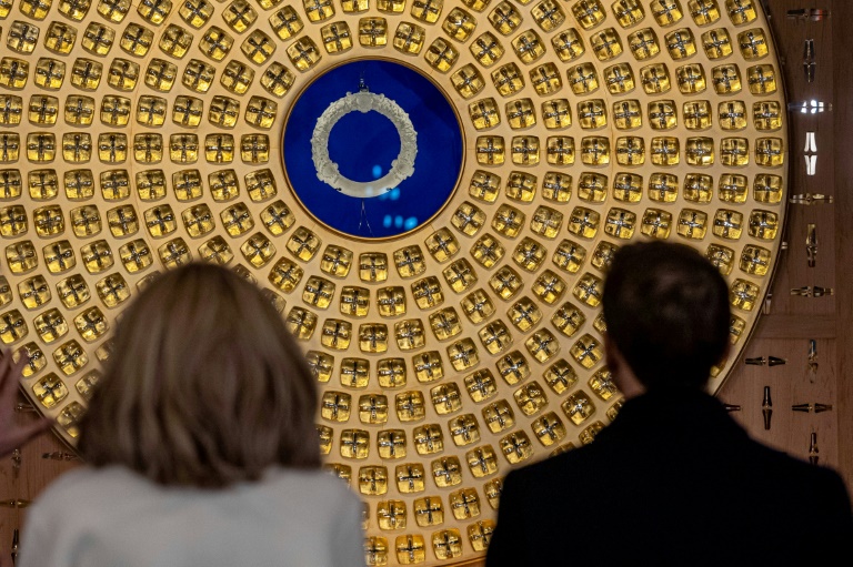 Brigitte et Emmanuel Macron regardent la couronne d'épines et le reliquaire conçus par l'artiste français Sylvain Dubuisson lors de leur visite à la cathédrale Notre-Dame de Paris, le 29 novembre 2024