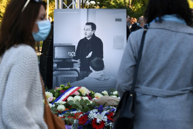 Des personnes devant un portrait de Samuel Paty lors d'une cérémonie d'hommage à l'enseignant, le 16 octobre 2021 à Eragny-sur-Oise (Val-d'Oise)