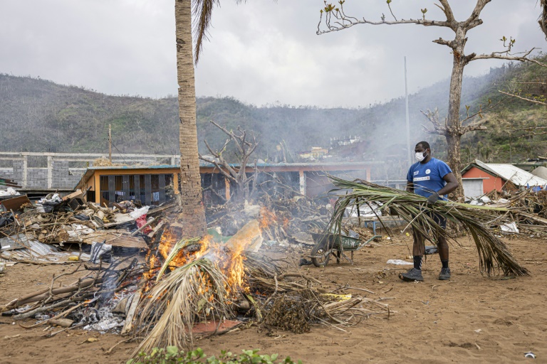 Un habitant de Mayotte fait brûler des branches de palmiers arrachées sur la plage à Acoua, le 25 décembre 2024