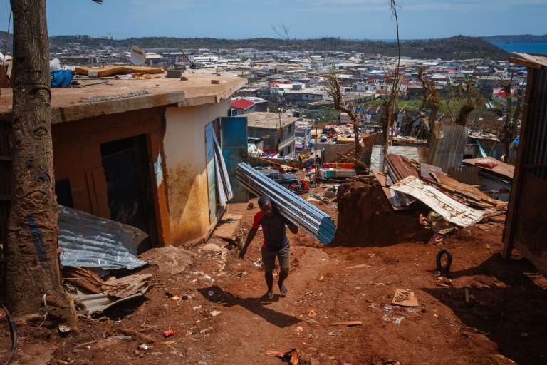 Un habitant du bidonville de Kawéni transporte des tôles pour renconstruire sa maison détruite par le passage du cyclone Chido, le 20 décembre 2024 à Mamoudzou