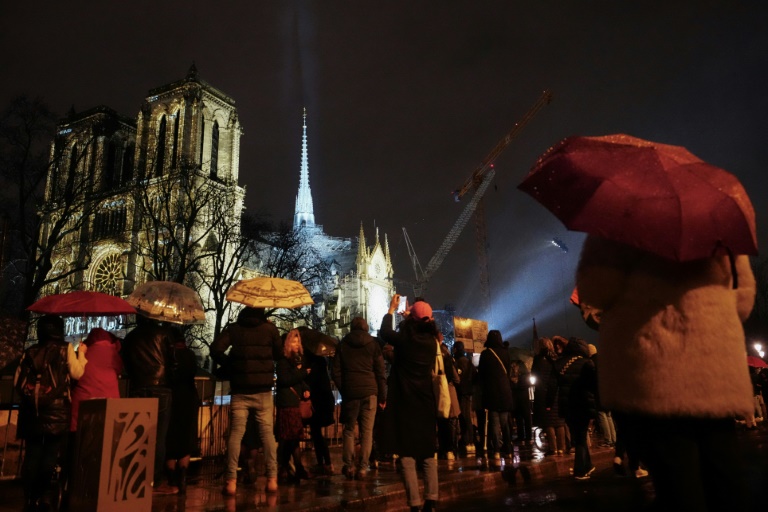 Une foule rassemblée sous la pluie devant la cathédrale Notre-Dame de Paris lors d'une cérémonie marquant sa réouverture officielle, le 7 décembre 2024 à Paris