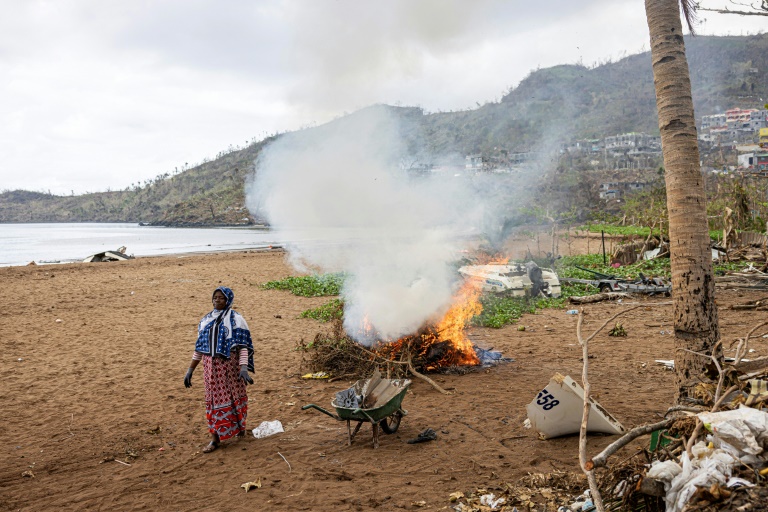 Une habitante de Mayotte fait brûler des branches de palmiers arrachées sur la plage à Acoua, le 25 décembre 2024