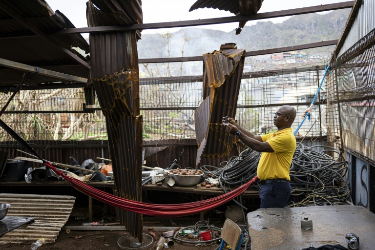 Un fonctionnaire prend une photo avec son téléphone portable pour évaluer les dégâts à l'intérieur d'une propriété à Acoua, plusieurs jours après le passage du cyclone Chido à Mayotte, le 25 décembre 2024