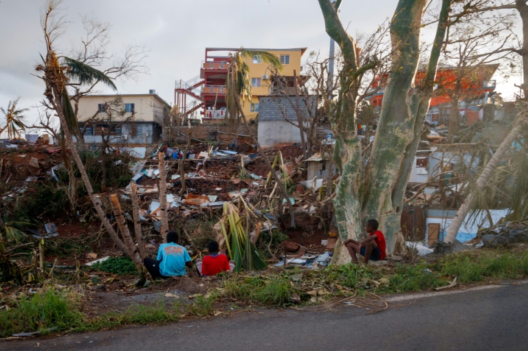 Des habitants assis devant leurs maisons détruites à Mamoudzou après le passage du cyclone Chido à Mayotte, le 17 décembre 2024