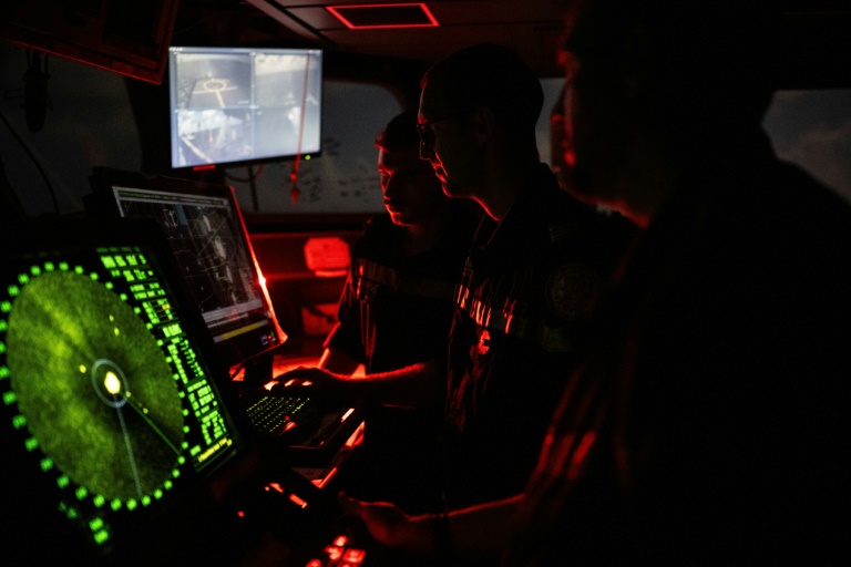 Le capitaine Frédéric Ollive (c) de la Marine française surveille les moniteurs du radar de la passerelle de contrôle lors d'une mission d'interception anti-drogue de la frégate de surveillance FS Ventose au large de la Martinique, le 16 novembre 2024 aux Antilles