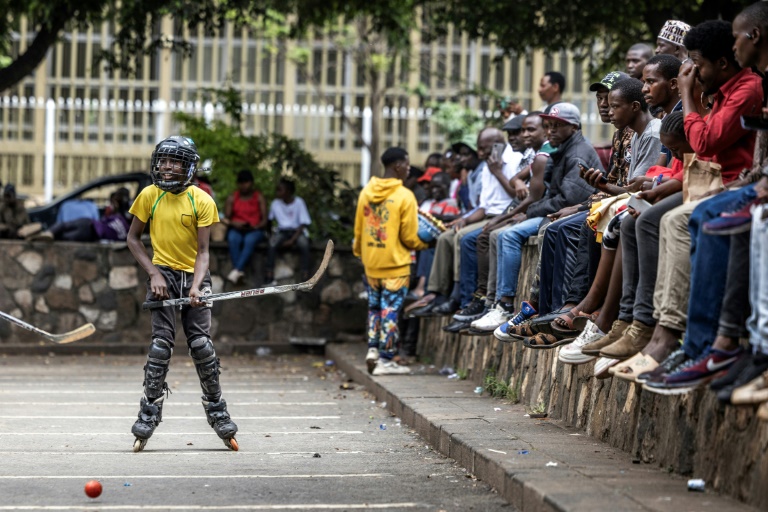 Un jeune joueur s'entraîne sur des rollers avec quelques membres de l'équipe nationale kenyane de hockey sur glace, sur un parking du centre de Nairobi, le 26 janvier 2025