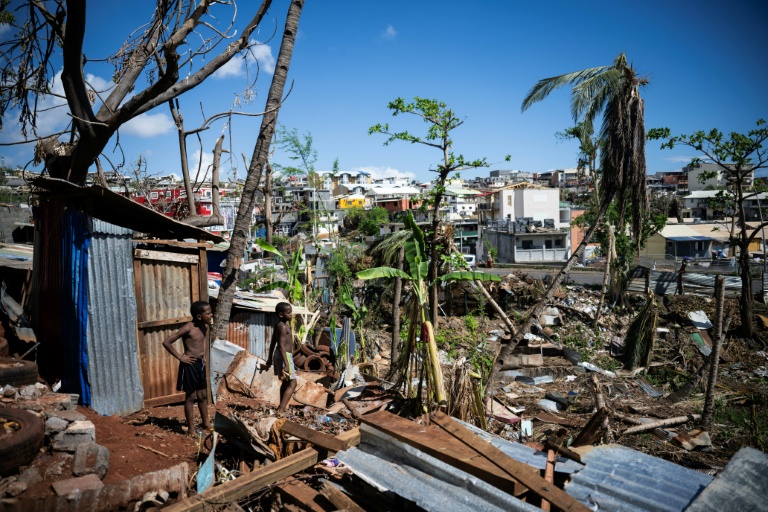 Des enfants au milieu des maisons détruites d'un bidonville endommagé par le cyclone Chido à Mamoudzou, sur le territoire de Mayotte, le 31 décembre 2024