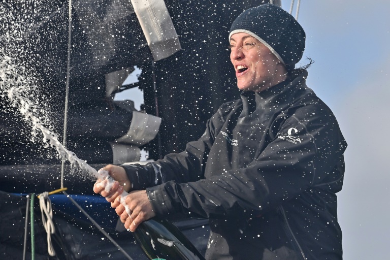 La navigatrice suisse Justine Mettraux sabre le champagne après son arrivée à la huitième place du Vendée Globe le 25 janvier 2025 aux Sables-d'Olonne