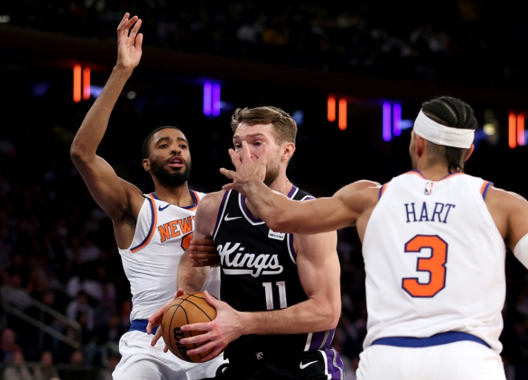 Domantas Sabonis (c.), le pivot des Sacramento Kings, tente de passer Mikal Bridges et Josh Hart, des New York Knicks, lors d'un match de NBA, à New York, le 25 janvier 2025