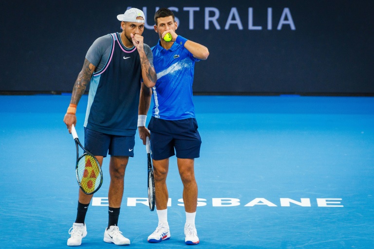 Le Serbe Novak Djokovic (d.) parle avec l'Australien Nick Kyrgios avant un point pendant leur match de double contre le Néo-Zélandais Michael Venus et le Croate Nikola Mektic au tournoi ATP de Brisbane, à Brisbane (Australie), le 1er janvier 2025