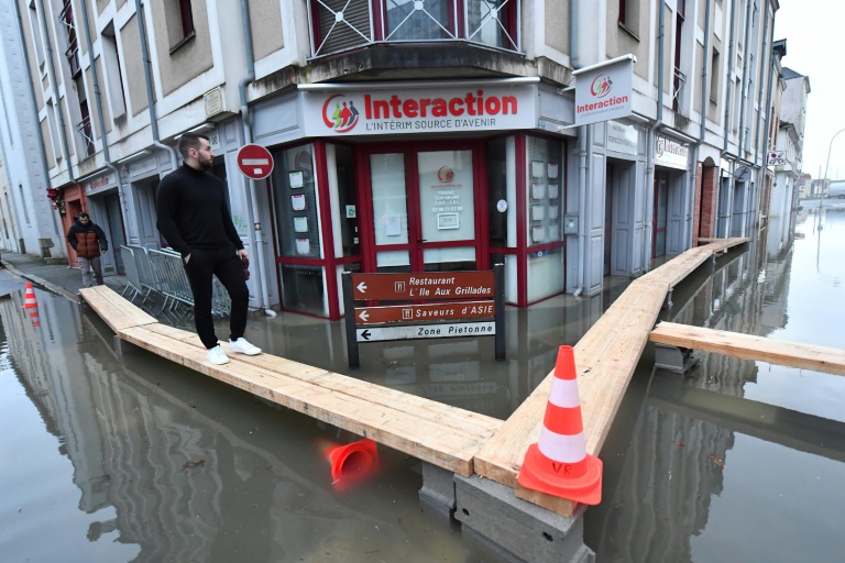 Un homme marche sur des planches dans une rue inondée après que la Vilaine soit sortie de son lit à Redon, en Ille-et-vilaine, le 29 janvier 2025