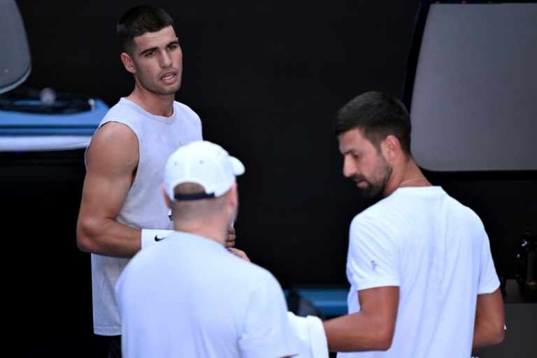 L'Espagnol Carlos Alcaraz (à gauche) discute avec le Serbe Novak Djokovic (à droite) lors d'une séance d'entraînement avant l'Open d'Australie à Melbourne, le 7 janvier 2025