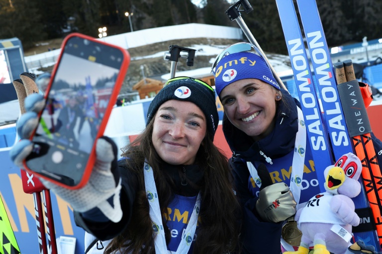 Julia Simon (D) pose avec la médaillé de bronze de l'individuel Lou Jeanmonnot, à Lenzerheide, en Suisse, le 18 février 2025