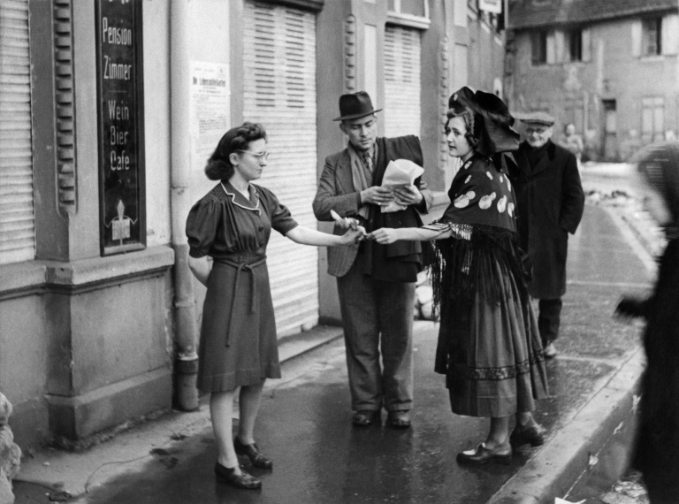 Une femme vêtue d'un costume traditionnel alsacien distribue des cadeaux des Alliés aux habitants de Colmar, libérée cinq jours plus tôt, le 7 février 1945