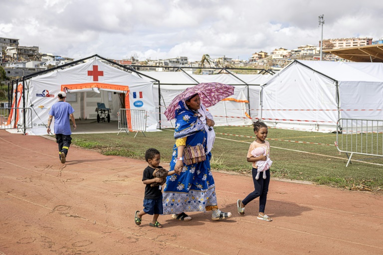 Une femme et ses enfants quittent l'hôpital de campagne installé dans le stade de Cavani, à Mamoudzou, le 24 décembre 2024 sur l'île de Mayotte