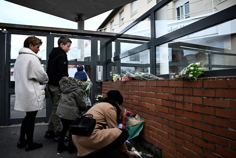 Une femme laisse un bouquet de fleurs au collège André Maurois à Epinay-sur-Orge(Essonne) le 8 février 2025