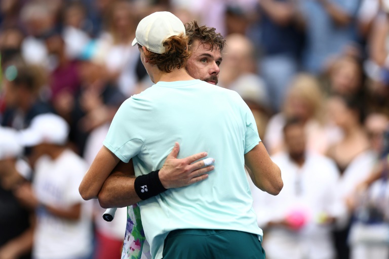 Le Suisse Stan Wawrinka étreint l'Italien Jannik Sinner (de dos) après avoir été battu dans leur match du troisième tour du simple masculin de l'US Open 2023, à New York, le 2 septembre 2023