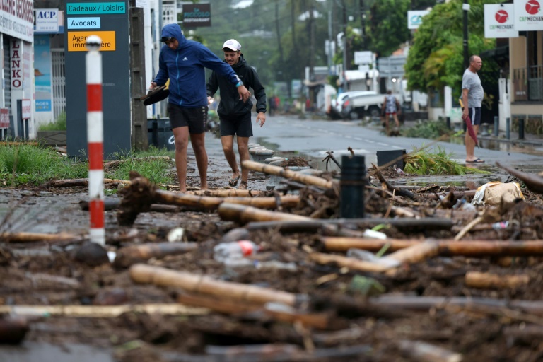 Des piétons au milieu des débris à Saint-Paul de la Réunion après le passage du cyclone Garance le 28 février 2025